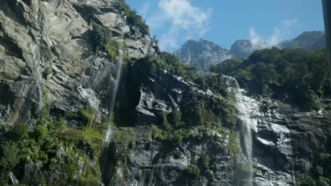 Waterfall pouring down cliff with mountain above at Milford Sound Stock Footage 260370518