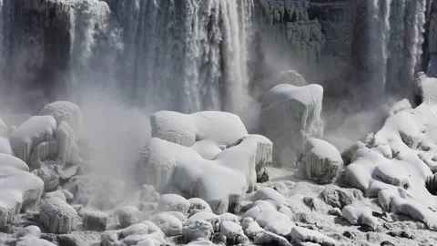 Waterfall pouring down on to the snowy rocks in winter Stock Footage 208677593