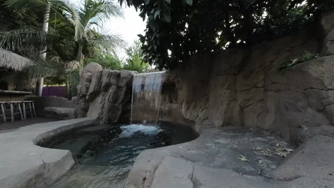 Waterfall pouring into a rock pool on a backyard patio Stock Footage 345544799
