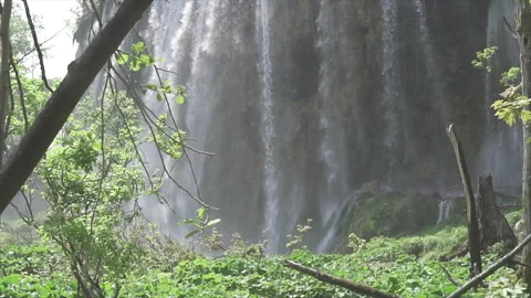 Waterfall pouring into turquoise pool under cloudy sky Stock Footage 319781822