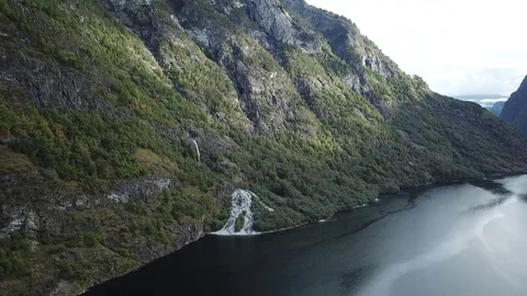 Waterfall Pours Down Forest Covered Cliffs into a Fjord Stock Footage 81492246
