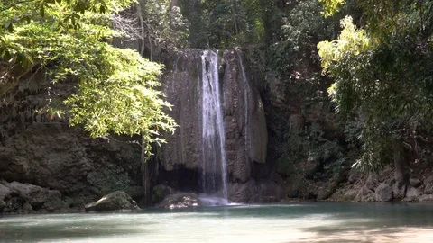 A waterfall pours into a pool of water covered in sunlight Video stock 74292140
