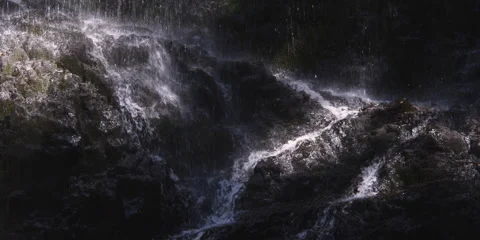 A waterfall raining onto dark rocks and streaming through narrow channels Stock Footage 59528361