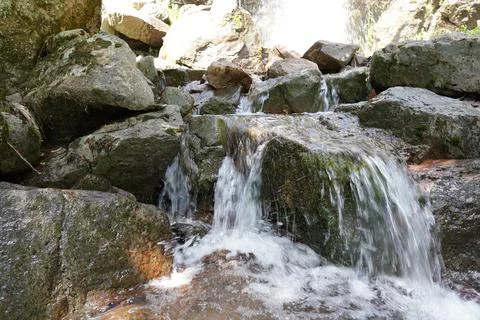 Waterfall reflecting sunlight between cliffs Stock Photos