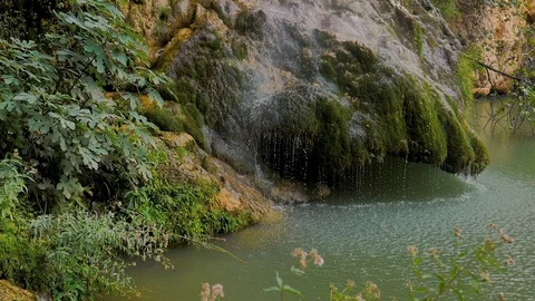 Waterfall in slow motion on rock with moss and green lagoon Stock Footage 124389864