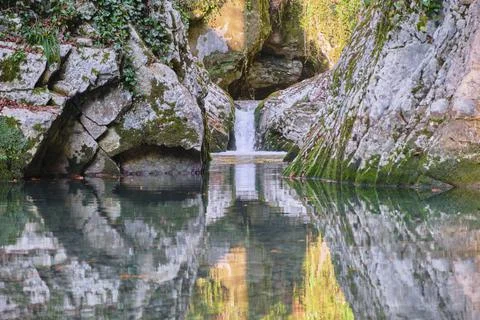 Waterfall in a stone gorge flows into the lake Stock Photos