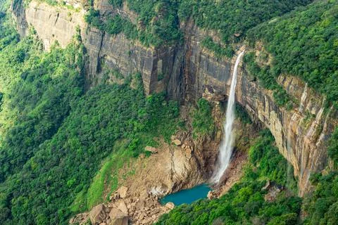 Waterfall streams falling from mountain top covered with green forests at day 스톡 사진