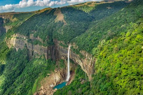 Waterfall streams falling from mountain top covered with green forests at day 写真素材