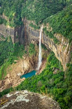 Waterfall streams falling from mountain top covered with green forests at day Foto stock