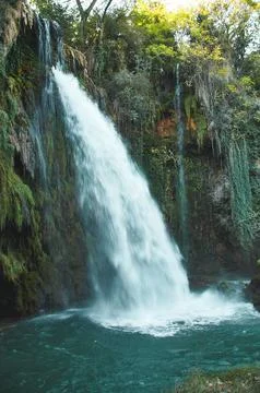Waterfall surrounded by lush greenery Stock Photos
