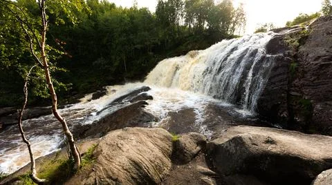 Waterfall surrounded by rocks and trees creates a scenic natural landscape Stock Photos