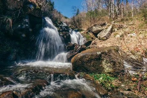 A waterfall surrounded by trees Stock Photos
