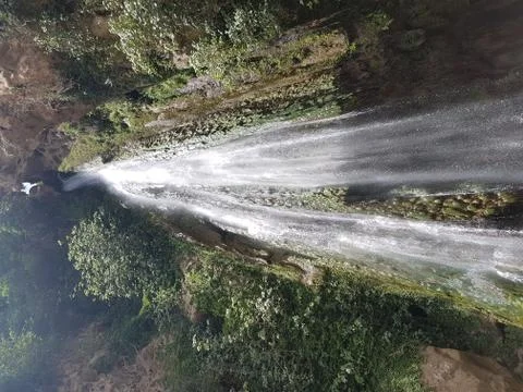 Waterfall through rocks and among green trees Stock Photos