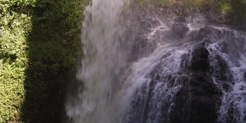 A waterfall throwing its shadow onto a mossy cliff over which if falls Stock Footage 59528391