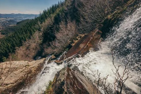 A waterfall with trees on the side of a mountain Foto stock
