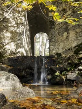 Waterfall under the bridge on the mountain river in autumn. Long exposure sho Stock Photos