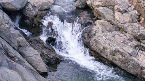 A waterfall where water is falling between the rocks Stock Photos