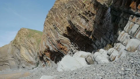 Waterfalls and the distinctive colourful strata cliffs at Sandymouth Beach Video stock 86498643