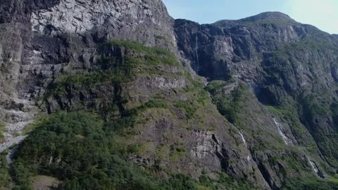 Waterfalls cascade down cliffs, surrounded by lush greenery, with a river below Stock-Footage 301383685