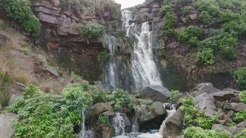 Waterfalls cascade down rugged, moss-covered cliffs Видео 342939985