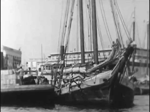 On the waterfront, barrels of seized rum are rolled along by dockworkers, in Stock Footage 74888743