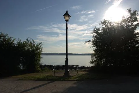 Waterfront Bench and Lamp Post Overlooking Calm River Stock Photos