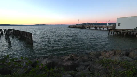 Waterfront with pier in background at sunset Stock Footage 203968742