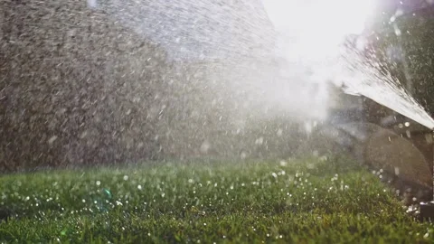 Watering the grass. SLOW MOTION. Water spraying out of sprinkler on the lawn. 動画素材 140295853
