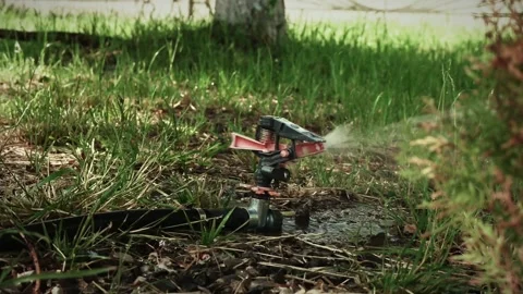 Watering machine spins around the axis and sprays water around in slow motion, Stock Footage 196887524