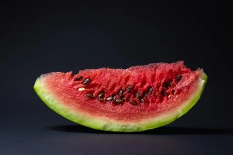 Watermelon on a black background. Cut off a slice of watermelon. Stock Photos