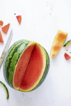 Watermelon with knife on white table flat lay Stock Photos