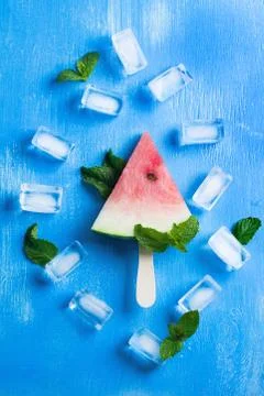 Watermelon popsicle mint leaves ice cubes on blue wooden background Stock Photos