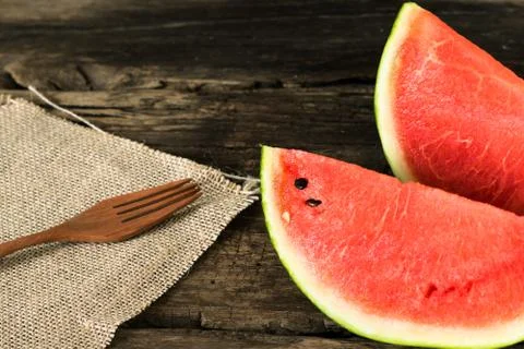 The watermelon on a rustic wooden table background with wood fork and sack .. Stock Photos