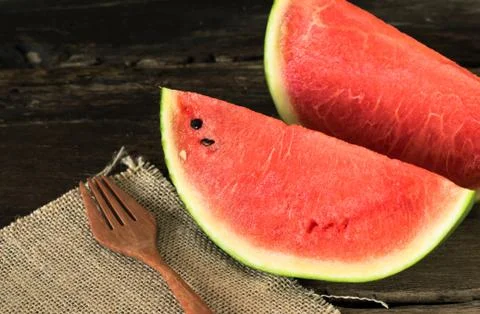 The watermelon on a rustic wooden table background with wood fork and sack .. Stock Photos