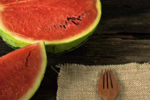 The watermelon on a rustic wooden table background with wood fork and sack .. Stock Photos