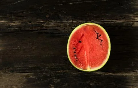The watermelon is slice of half on a rustic wood background. copy space for.. Stock Photos