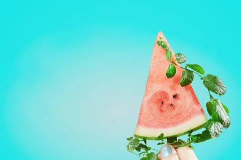 Watermelon Slice with Mint Held Against Blue Background Foto stock