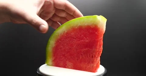 Watermelon slice resting and turning man grabbing and eating slice of melon Stock Footage 205330421