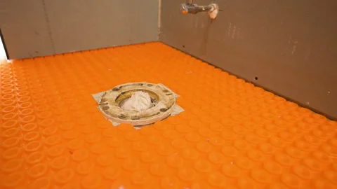 Waterproofing membrane installed on a bathroom floor around a toilet flange Stockbeeldmateriaal 346802327