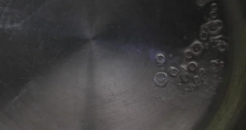 Water's boiling on the hot pan, and tiny bubbles are popping up all over Stock Footage 256285295