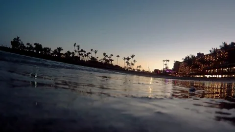 Water's edge next to hotels and palms at night Stockbeeldmateriaal 79734368