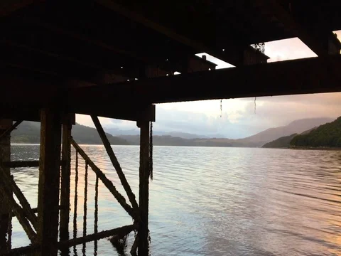 Waters flow and ripple underneath the wooden dock of Loch Sunart 4K as the sun Stock-Footage 79884936