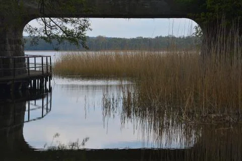 Waterway between two lakes, view through a railway bridge span Stock Photos