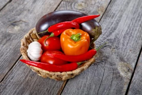 Wattled basket with vegetables on an old table Stock Photos