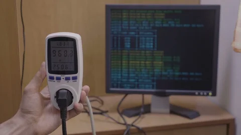 Wattmeter indicating power usage rate of cryptocurrency mining rig and pc wit Stock Footage 102474717
