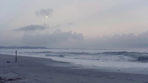 Wave Against on The Beach with Surfer, The Moon Appear on Twilight Sky Stock Footage 128948254