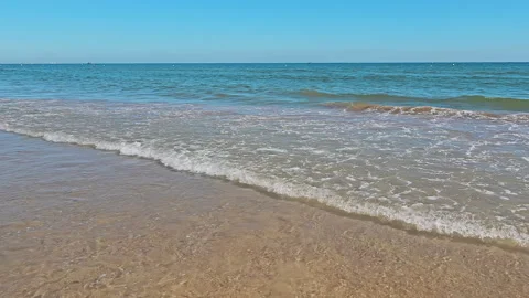 Wave Approaching Sandy Beach. Gentle waves rolling onto the shore of a sandy Stock Footage 258945428