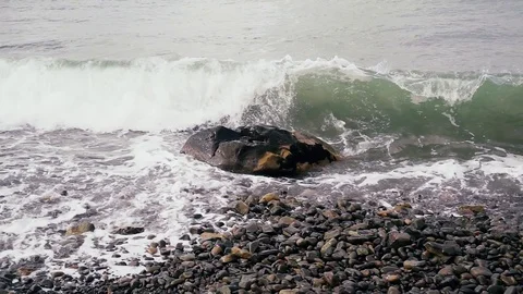 The wave beautifully splits against the stone on the shore slow mo Stock Footage 82930197