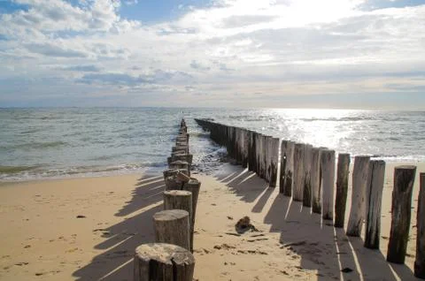 Wave breakers at the beach with clouds Stock Photos