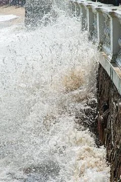 Wave breaking against a stone wall Stock Photos